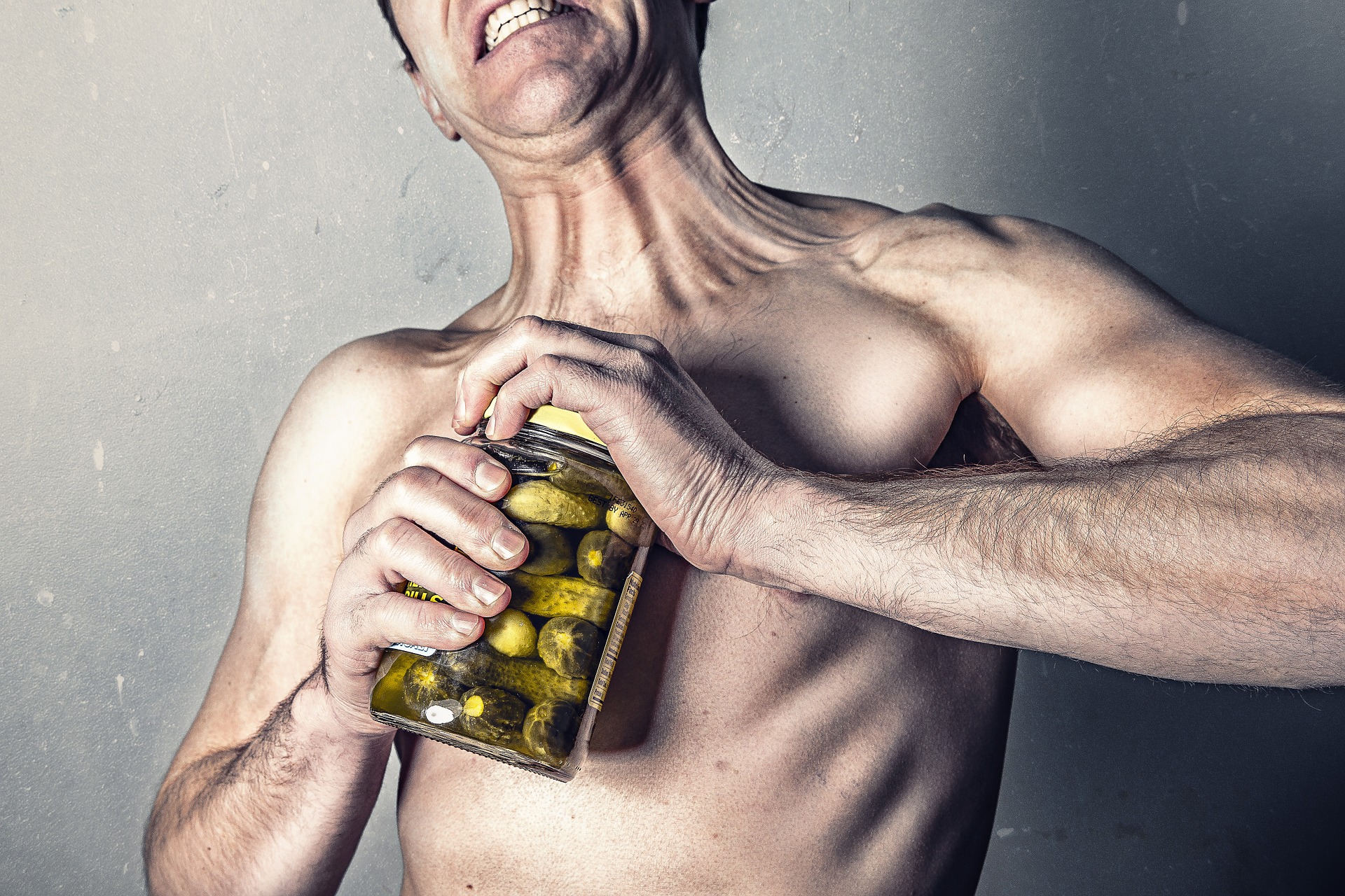 shirtless man attempting to open jar