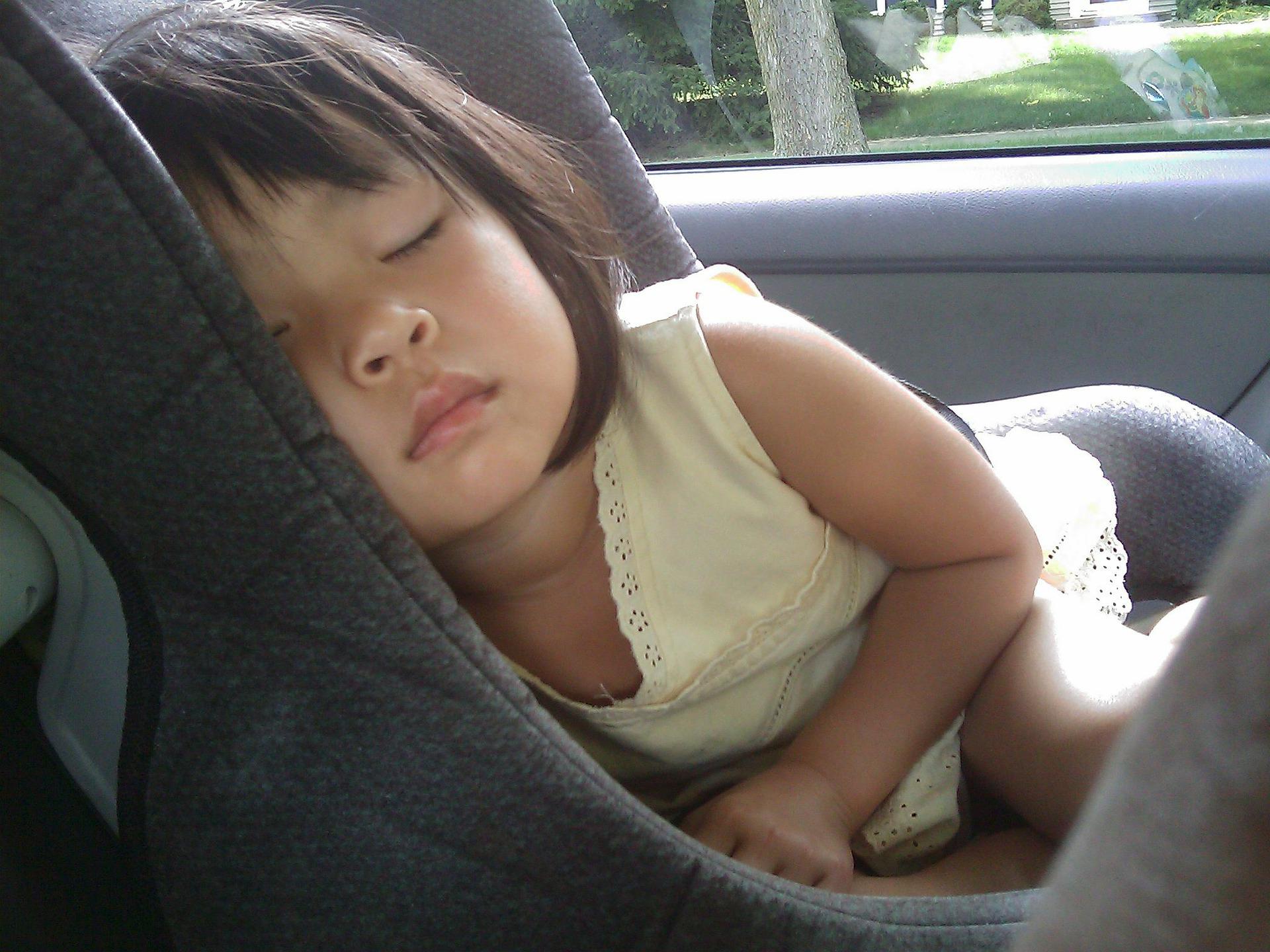 Little girl sleeping in a booster seat.
