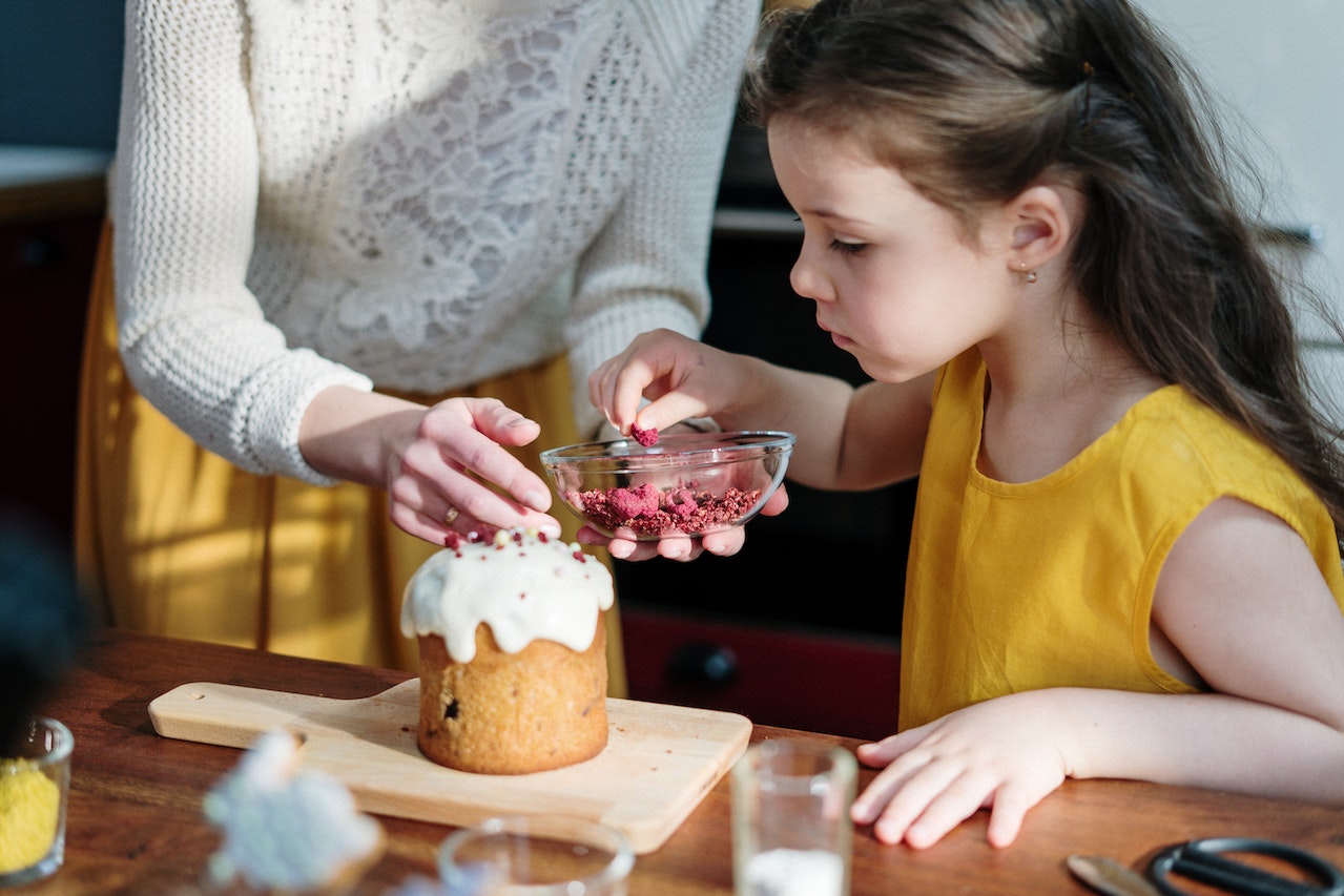 Little girl baking a cake with her mom